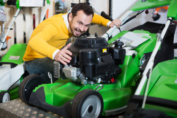 Man choosing lawnmower Attractive young  man choosing lawnmower in garden equipment shop launch tower stock pictures, royalty-free photos & images