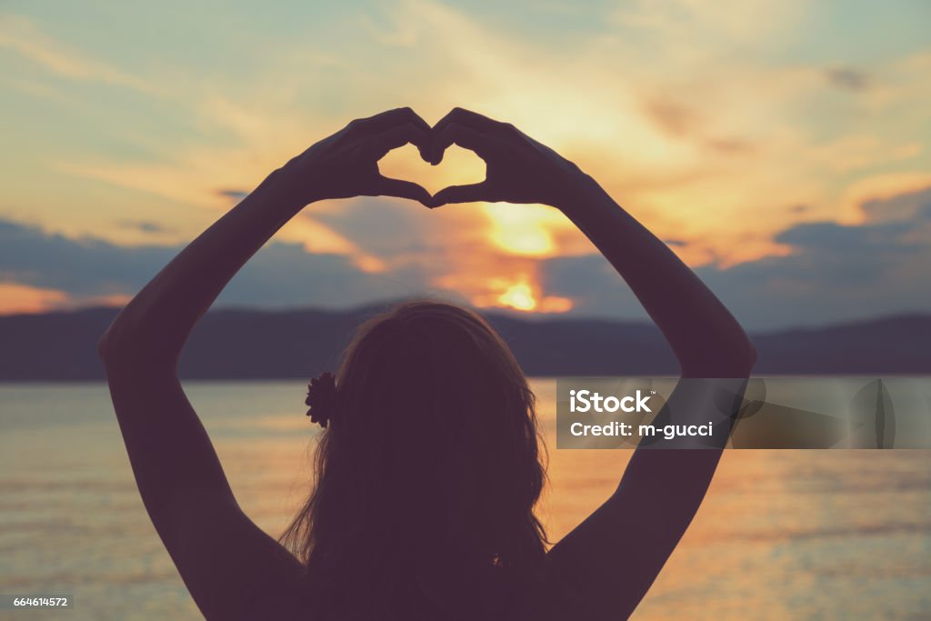 Girl holding a heart shape for the ocean / sea. Adult Stock Photo
