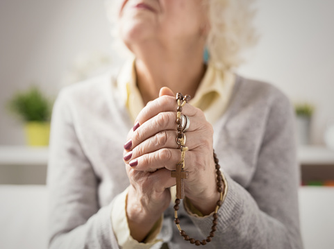 Grandma prayng with wooden  rosary in her hands