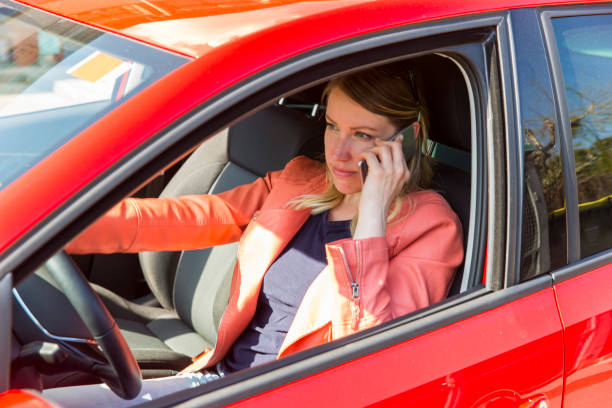 istock Young woman driving a car and using mobile phone 664627470