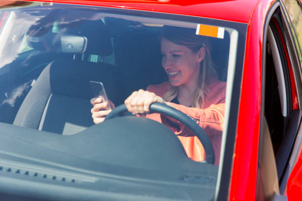istock Young woman driving a car and using mobile phone 664627616