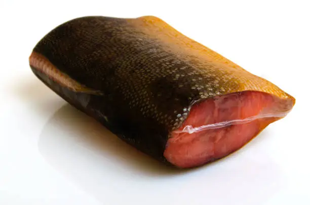 A piece of pink salmon smoked in a vacuum package against a light background.