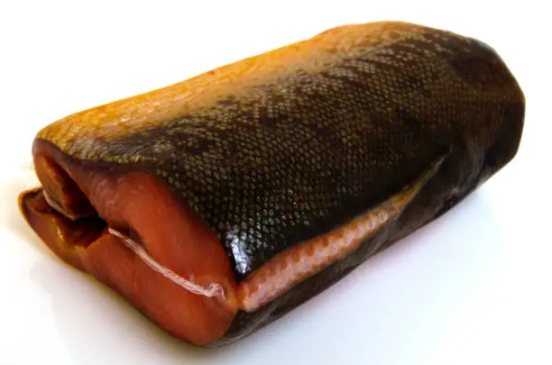 A piece of pink salmon smoked in a vacuum package against a light background.