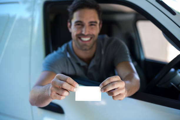 istock Smiling driver man showing blank card 664631224
