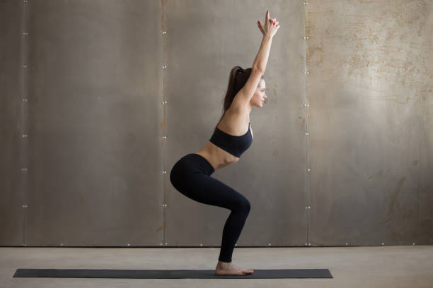 istock Young attractive woman standing in Utkatasana pose, grey studio 664635242