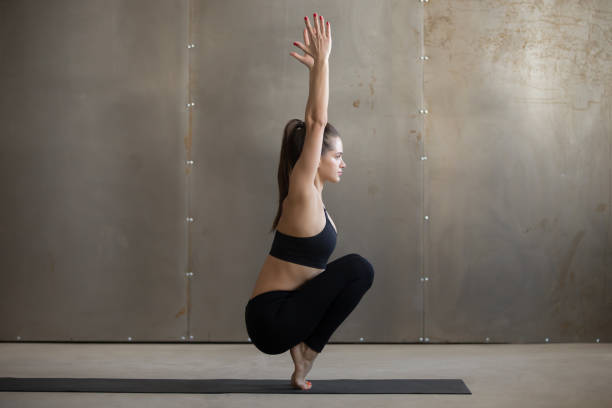 istock Young attractive woman in Utkatasana pose, grey studio backgroun 664635244