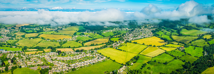 Aerial panoramic view over rural homes surrounded by picturesque green pasture and patchwork farmland.