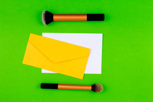 istock Make up brushes with yellow envelope and white blank card on greenery background 664642238