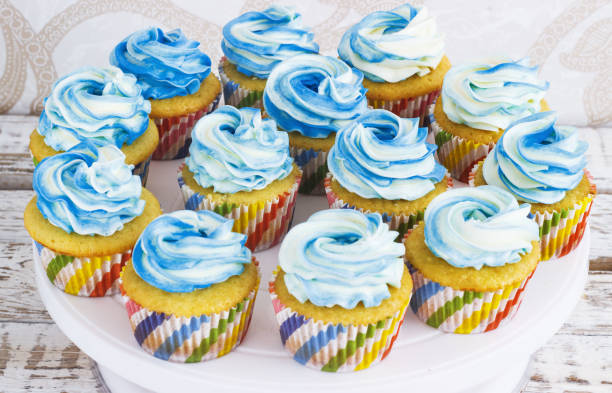 istock Festive cupcakes with cream in blue on a white wooden background 664653234