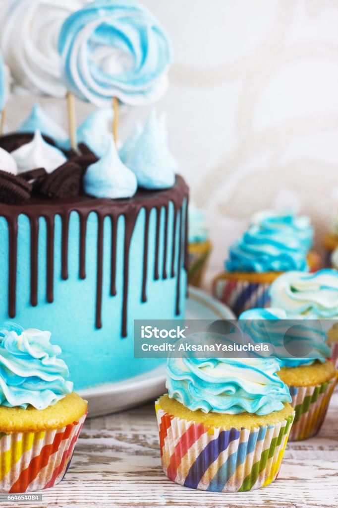 Festive cupcakes and cake with cream in blue on a white wooden background Festive cupcakes and cake with cream in blue on a white wooden background. Backgrounds Stock Photo