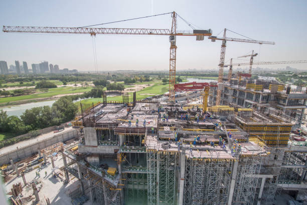 Building with Cranes. Construction cranes over Dubai cityscape stock photo