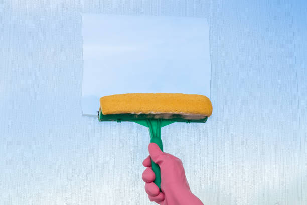 istock Hand in glove washing and cleaning window with professionally squeegee. 664657704