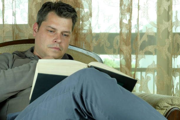 istock Young man reading a book in a chair 664660254