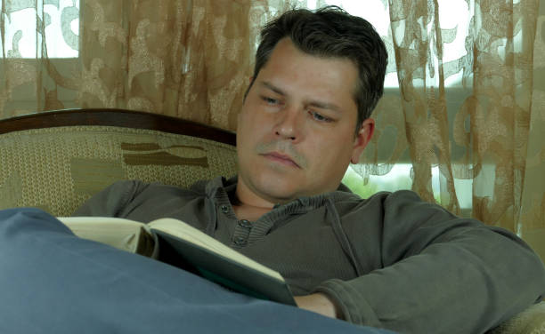 istock Young man reading a book in a chair 664660386