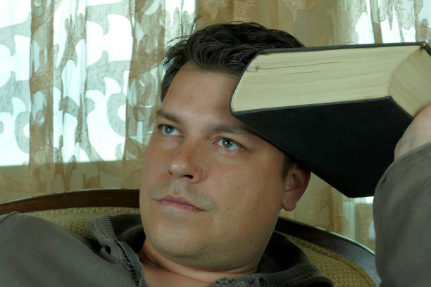 istock Young man reading a book in a chair 664660418
