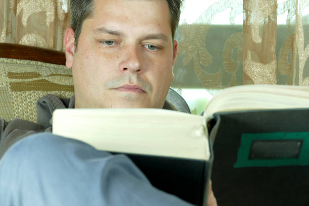 istock Young man reading a book in a chair 664660428