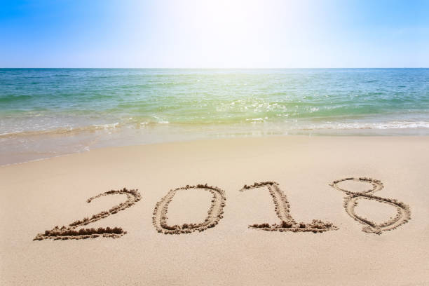 istock Year 2018 written at the sand beach with sea wave water 664660588