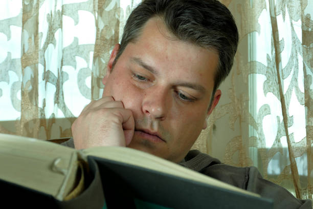 istock Young man reading a book in a chair 664663782