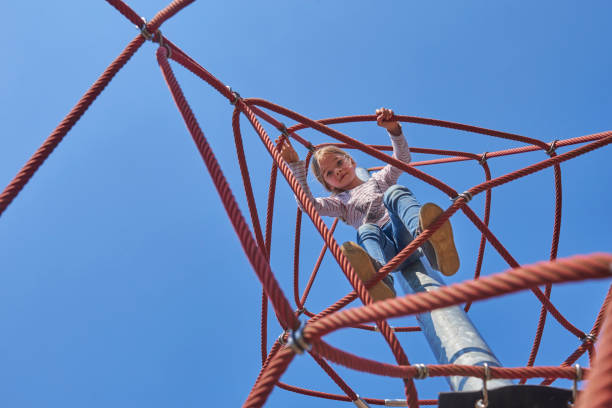 istock Active young child girl climbing the spider web playground activity. 664663856