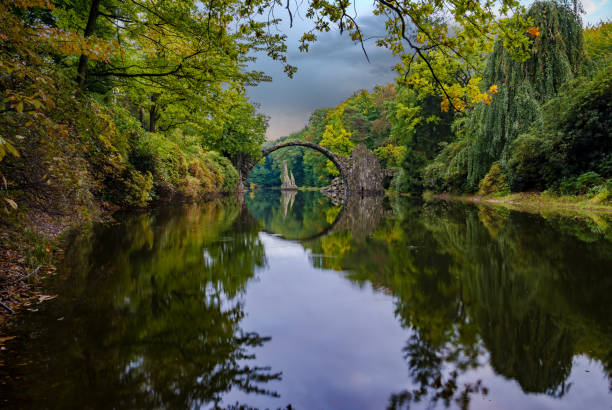 istock Autumn, cloudy evening over Devil's bridge in the park Kromlau, Germany 664667940