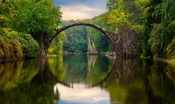 Photo of Autumn, cloudy evening over Devil's bridge in the park Kromlau, Germany
