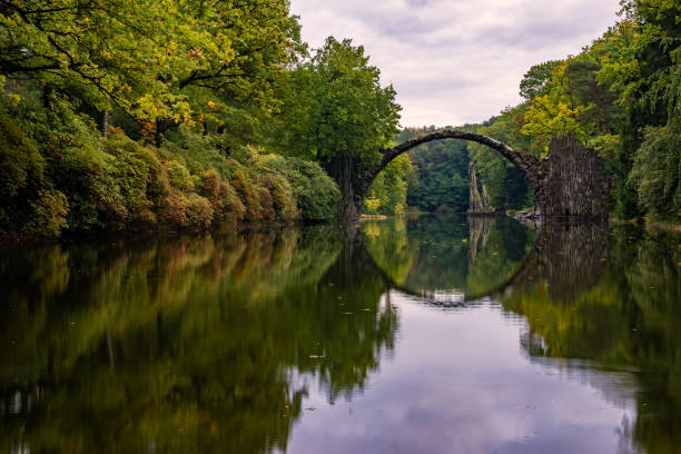 istock Autumn, cloudy evening over Devil's bridge in the park Kromlau, Germany 664669442