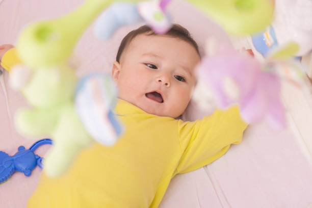 istock Baby lying in his crib reaching for toy curiously 664677514