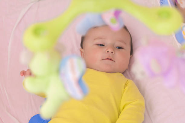 istock Baby lying in his crib reaching for toy curiously 664679642