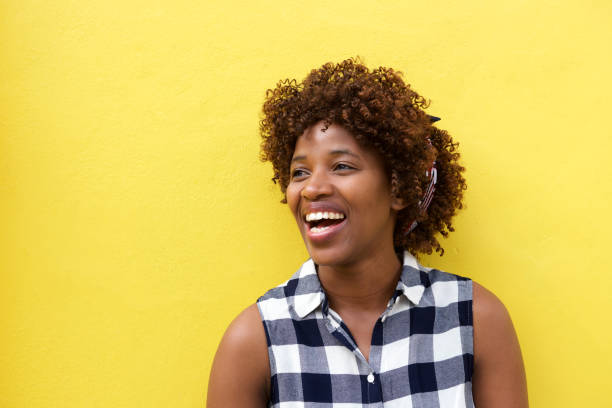 istock african woman laughing against yellow background 664679968
