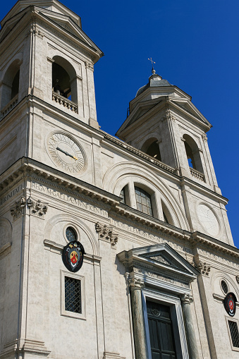 The church of the Santissima Trinità dei Monti, commonly known as the Trinità dei Monti is a Roman Catholic Renaissance church in Rome, Italy.  It is located above the Spanish Steps which lead down to the Piazza di Spagna.  Vivid blue clear sky is in background.
