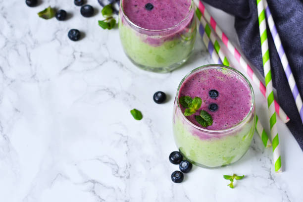 domowe koktajle z kiwi, szpinakiem i jagodami na marmurowym tle z gaz�ą - blueberry smoothie glass striped zdjęcia i obrazy z banku zdjęć