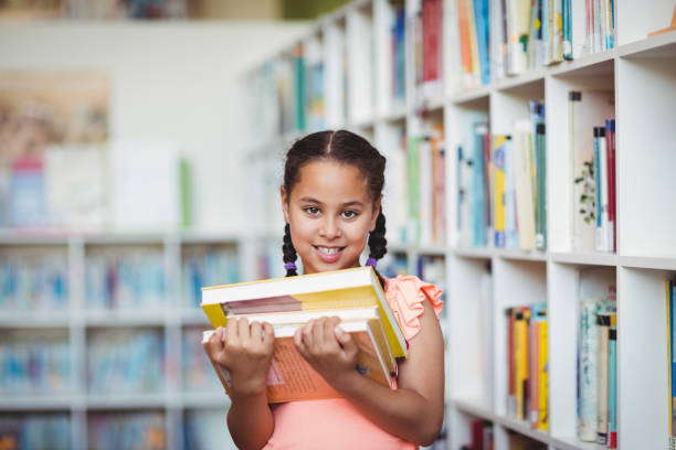 Smiling girl holding books in the library