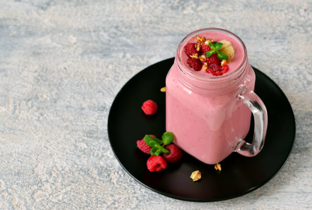 Raspberry smoothie with banana, yogurt and oatmeal on a gray, concrete background. stock photo