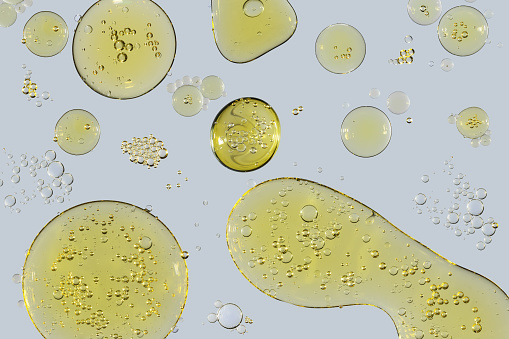 Drops and bubbles of vegetable oil on a light gray background close-up