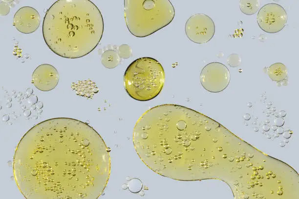 Drops and bubbles of vegetable oil on a light gray background close-up