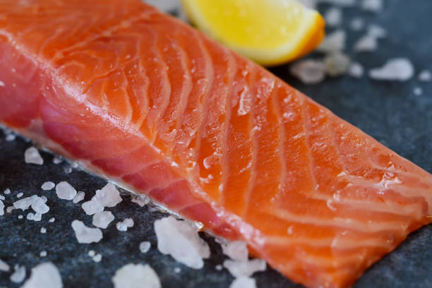 istock Salted, marinated salmon with salt and lemon on black marble background 664687980