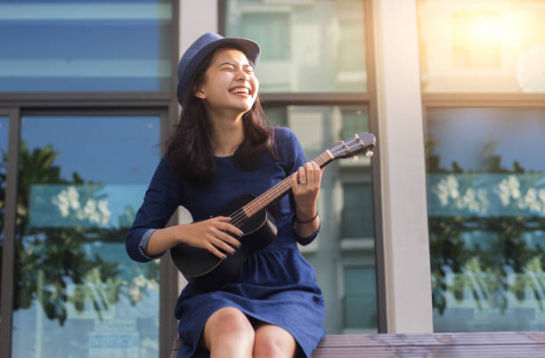 chica asiática divirtiéndose con ukelele - guitar playing music human face fotografías e imágenes de stock