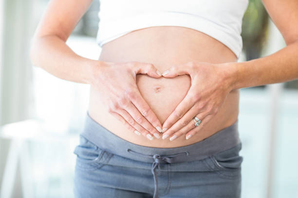 istock Midsection of woman hands making heart shape on belly 664696920