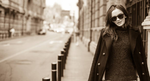 One woman, standing outdoors on the street, black and white.