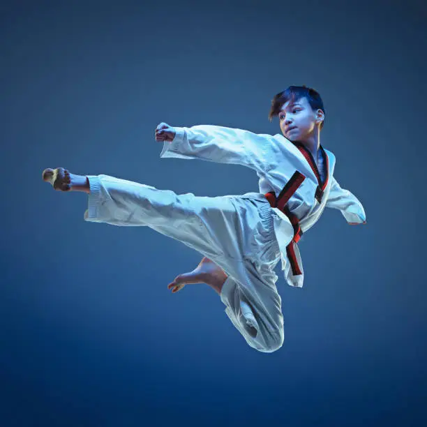 Photo of Young boy training karate on blue background