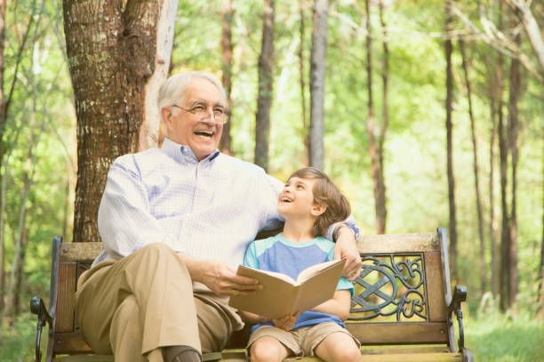 istock Grandfather and grandson reading books outdoors together. 664708032