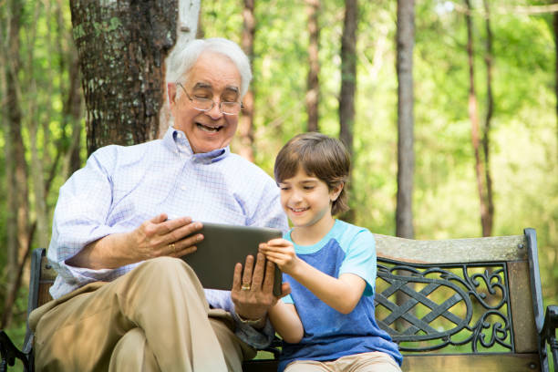 istock Grandfather and grandson using digital tablet outdoors together. 664713226
