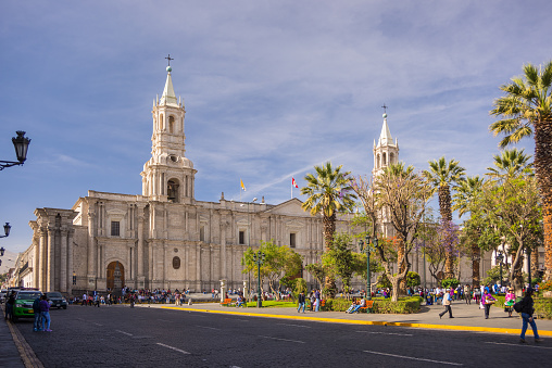 Arequipa, Peru - August 15, 2015: People on the main square, Plaza de Armas, of Arequipa, famous travel destination and landmark in Peru. The majestic Cathedral in the background. Scenic sky at sunset.