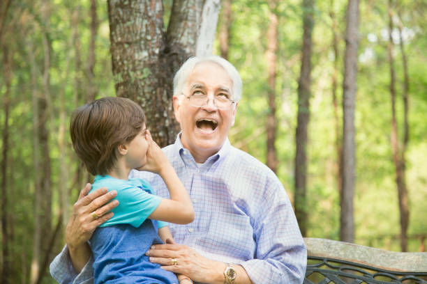 istock Grandfather and grandson tell secrets outdoors together. 664716682
