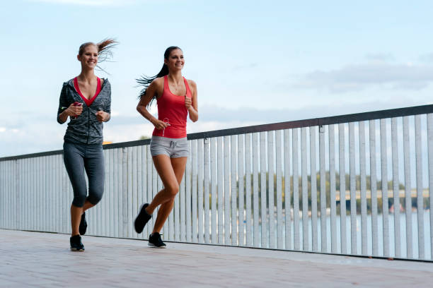 istock Two women exercising by jogging in city 664719538