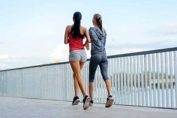 istock Two women exercising by jogging in city 664719944