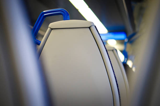 Horizontal colour image of the carriage of a commuter train in London, UK. Focus is on the chair in front, while other seats and the fluorescent light is blurred out of focus in the background. Room for copy space.