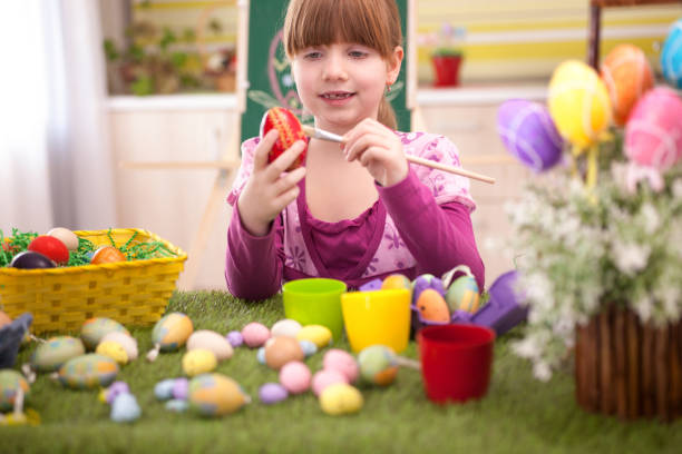 istock happy smiling young girl painting eggs in home kitchen 664732286