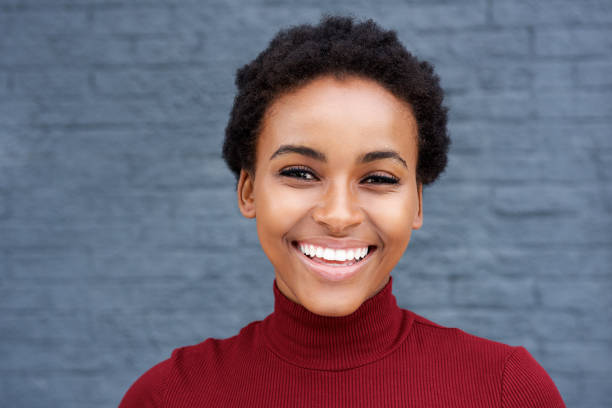 istock young african woman smiling against gray wall 664734606
