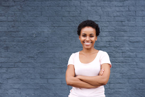 istock smiling black woman standing against gray wall 664734674